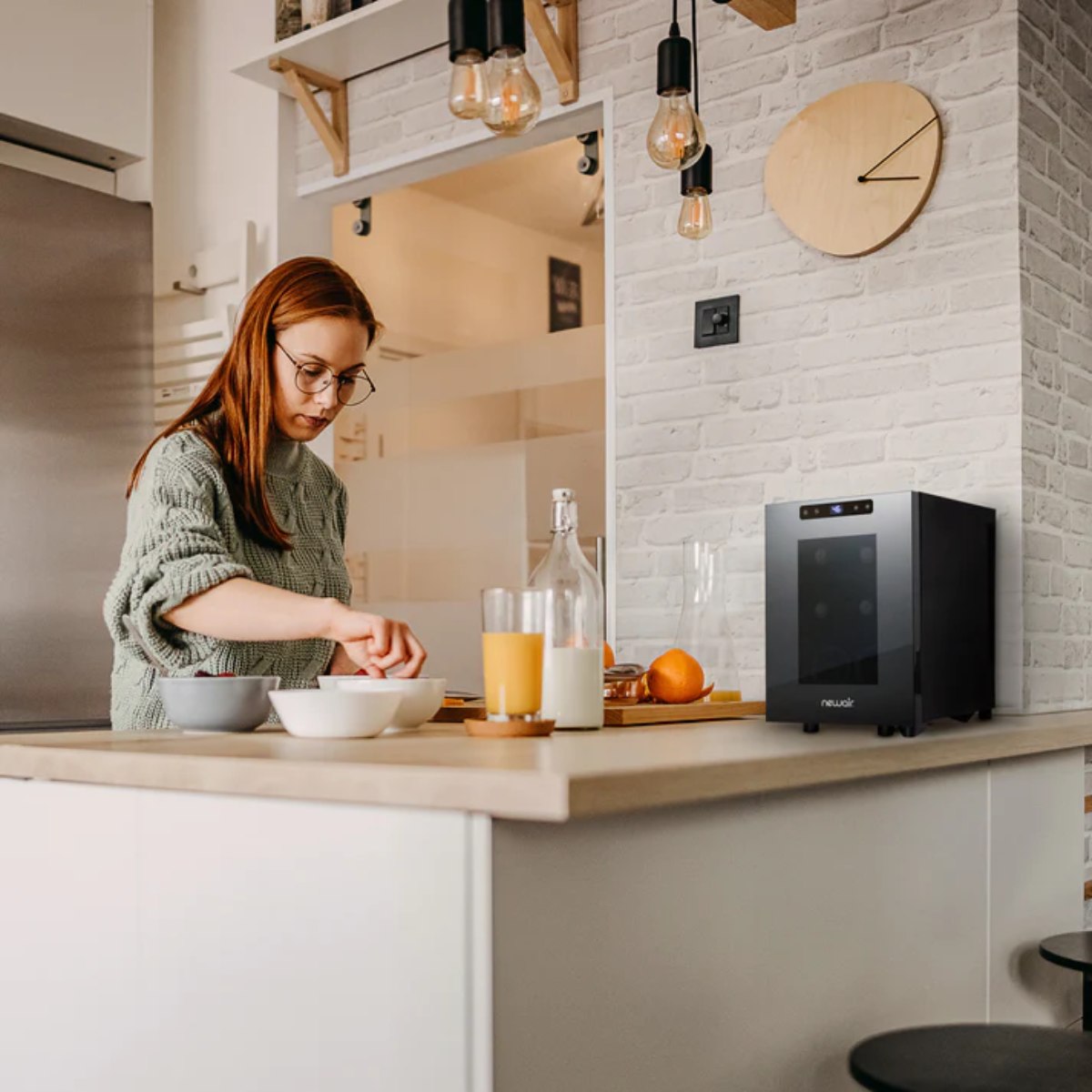 Newair 6 Bottle Shadow-T Series Freestanding Wine Fridge – 10.2" Black - Compact Fridge shown on top of the table with a woman preparing food and drinks
