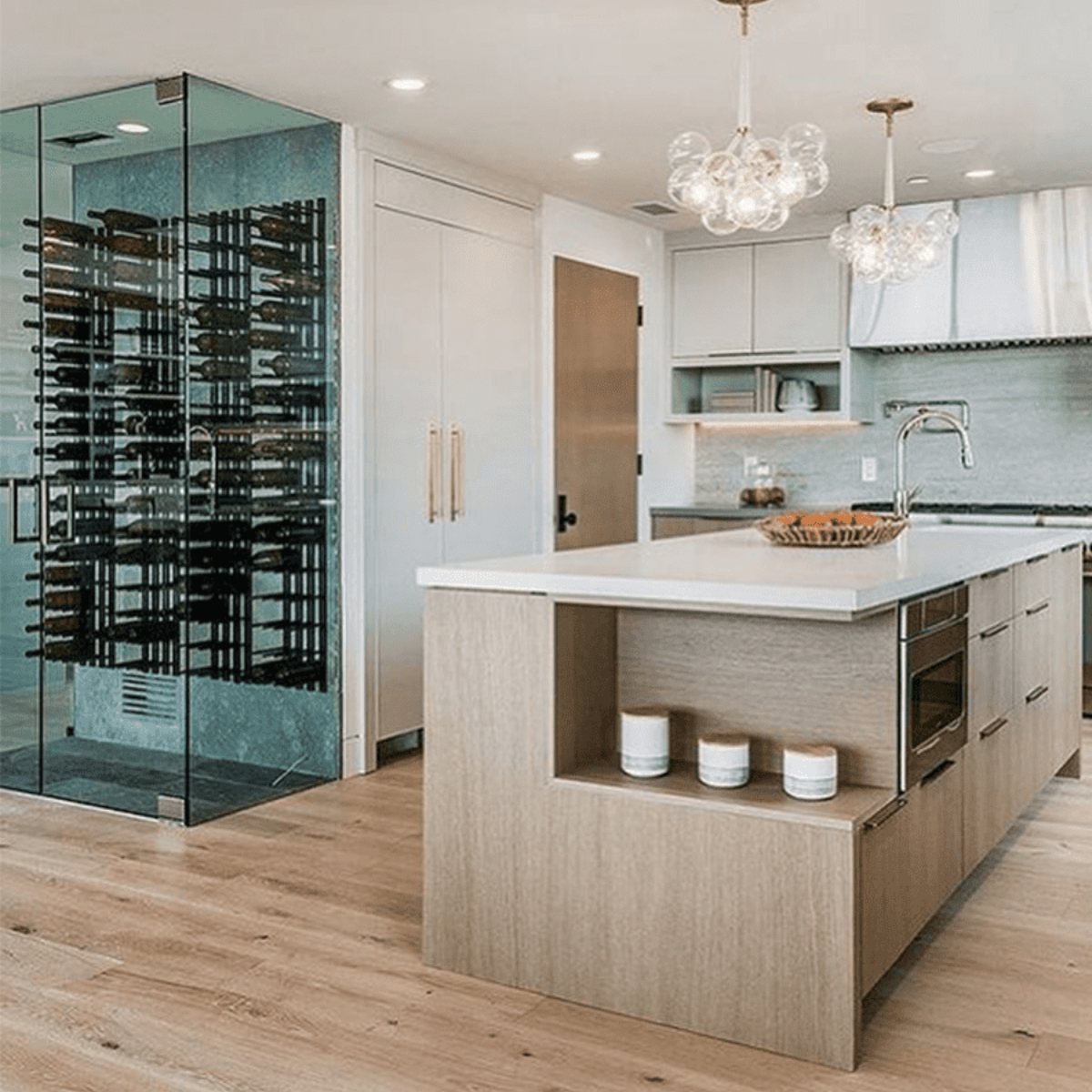 Ultra 2FT Cork-Out Straight Wall Rail Wine Rack (6 Bottles) - Modern kitchen with glass-enclosed wine cellar beside a large island and pendant lighting