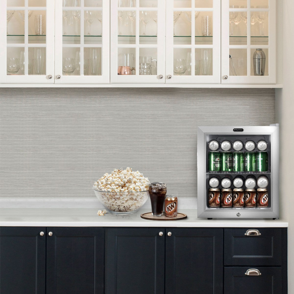 Whynter BR-062WS 68-Can Stainless Steel Beverage Refrigerator - fridge filled with soda cans on a kitchen counter beside popcorn and a drink