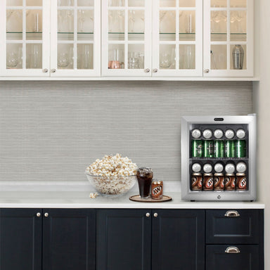Whynter BR-062WS 68-Can Stainless Steel Beverage Refrigerator - fridge filled with soda cans on a kitchen counter beside popcorn and a drink