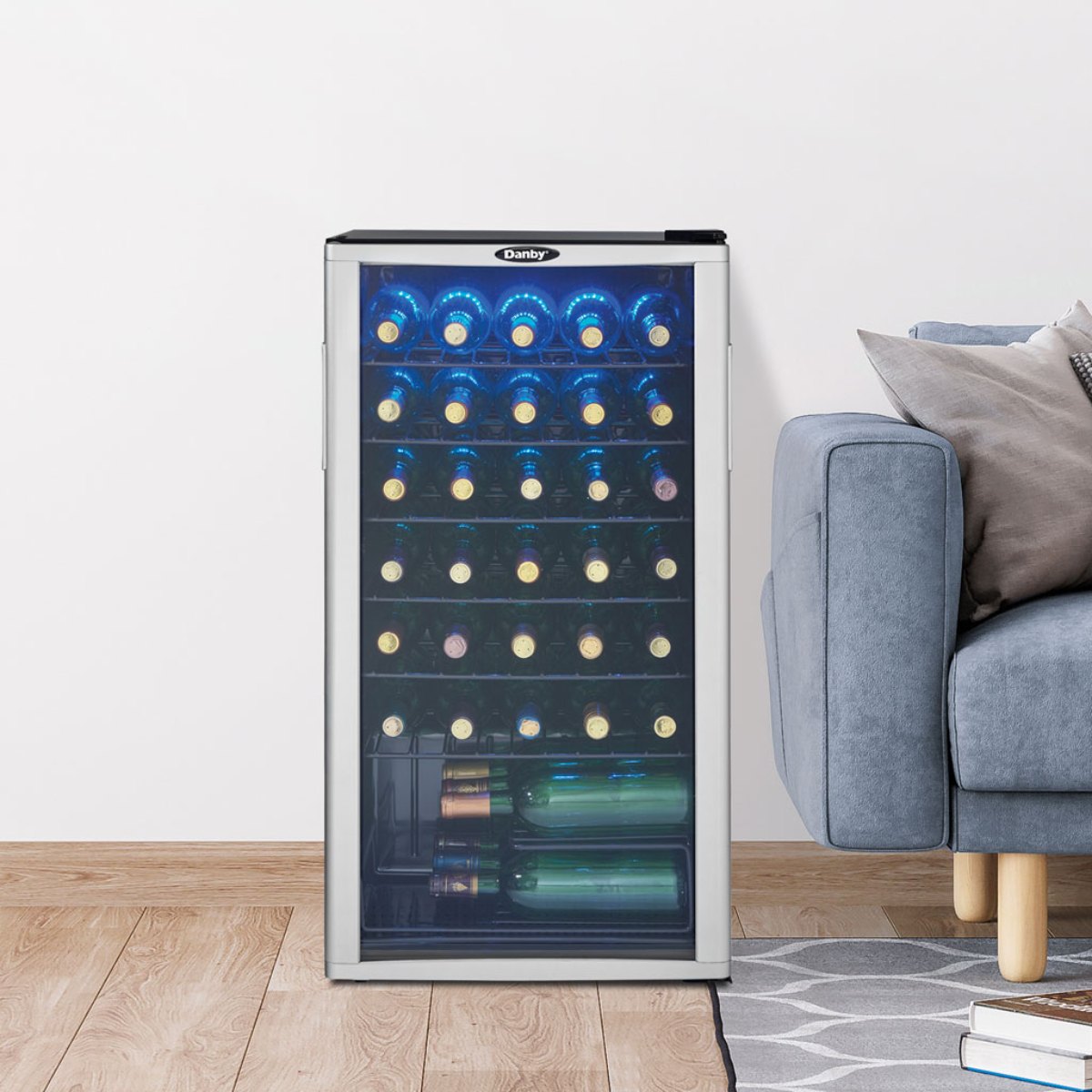 Danby 36 Bottle Freestanding Wine Cooler in Platinum - cooler with blue LED lighting beside a grey sofa on wooden flooring