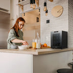 Newair 12 Bottle Shadow-T Series Wine Fridge – 9.9" Black - Compact Fridge shown on top of the table with a woman preparing foods and drinks