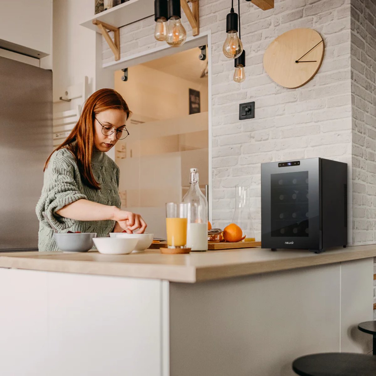 Newair 12 Bottle Shadow-T Series Wine Fridge – 9.9" Black - Compact Fridge shown on top of the table with a woman preparing foods and drinks