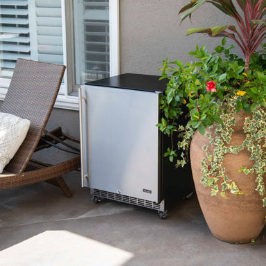 Newair 160-Can Outdoor Beverage Fridge – 24″ Built-In/Freestanding - beverage fridge beside a lounge chair and large potted plant