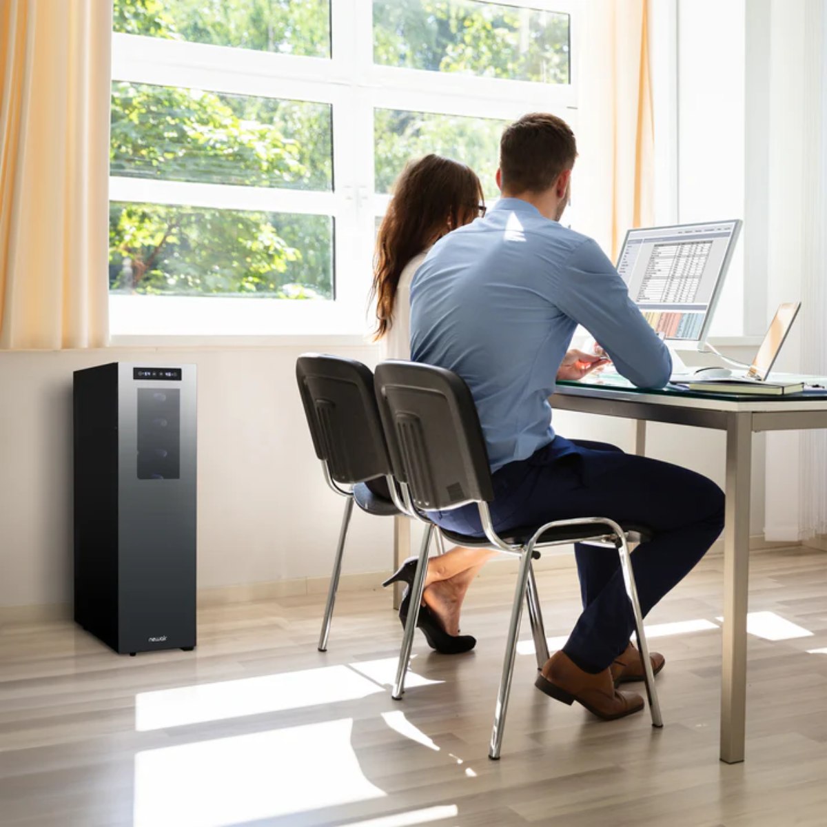 Newair 18 Bottle Shadow-T Series Wine Fridge – 10.75" Black - Two people working at a desk in a bright office with a sleek black Newair wine fridge in the corner