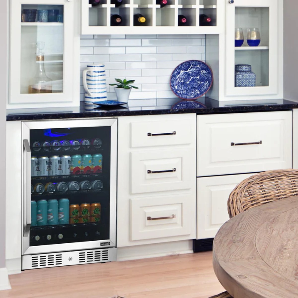 Newair 24” Built-in 177 Can Beverage Fridge in Stainless Steel - Compact beverage fridge filled with cans, integrated into white kitchen cabinetry