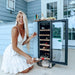 Newair 29 Bottle Dual Zone Wine Fridge – 14.8" Stainless Steel - Woman pouring wine beside a freestanding wine cooler on a patio