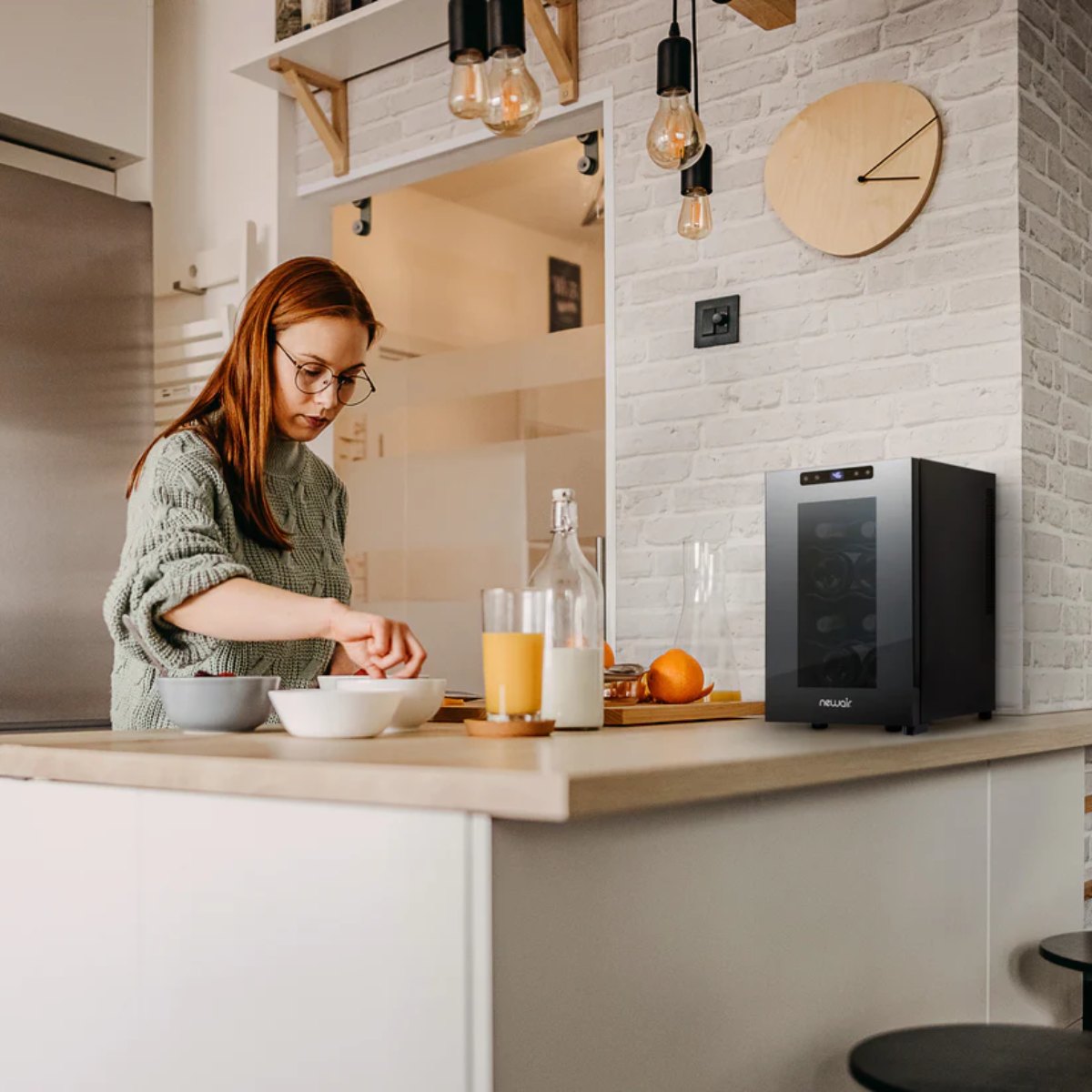 Newair 8 Bottle Shadow-T Series Wine Fridge – 10.2" Black - Compact Fridge shown on top of the table with a woman preparing foods and drinks