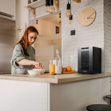 Newair 8 Bottle Shadow-T Series Wine Fridge – 10.2" Black - Compact Fridge shown on top of the table with a woman preparing foods and drinks