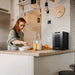 Newair 8 Bottle Shadow-T Series Wine Fridge – 10.2" Black - Compact Fridge shown on top of the table with a woman preparing foods and drinks