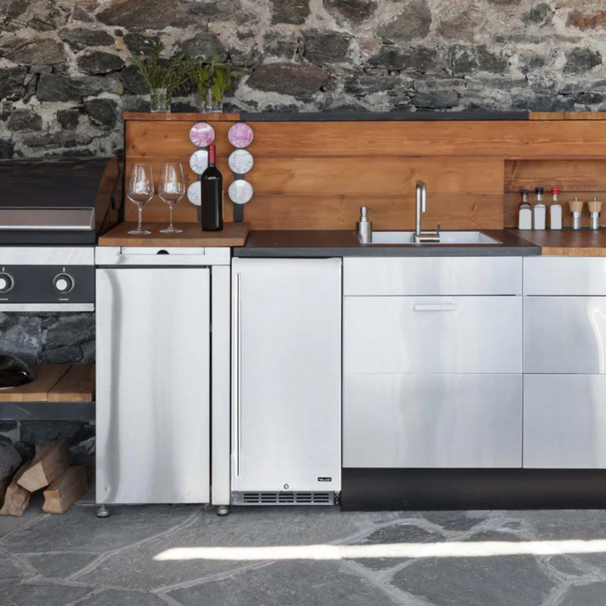 Newair 90-Can Outdoor Beverage Fridge – 15″ Built-In/Freestanding - Built-in stainless steel beverage fridge in an outdoor kitchen with stone and wood accents