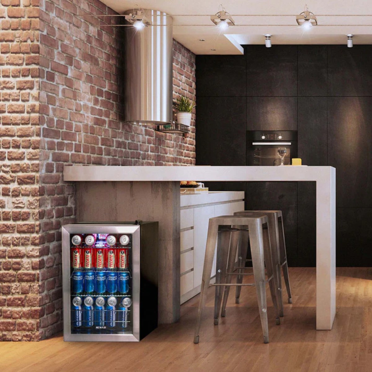 Newair 90 Can Freestanding Beverage Fridge – 17" Stainless Steel - placed under a bar counter in a modern kitchen with brick walls