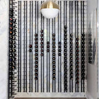 Ultra 2FT Cork-Out Straight Wall Rail Wine Rack (6 Bottles) - Floor-to-ceiling wine wall with black metal racks against a marble backdrop and modern light fixture