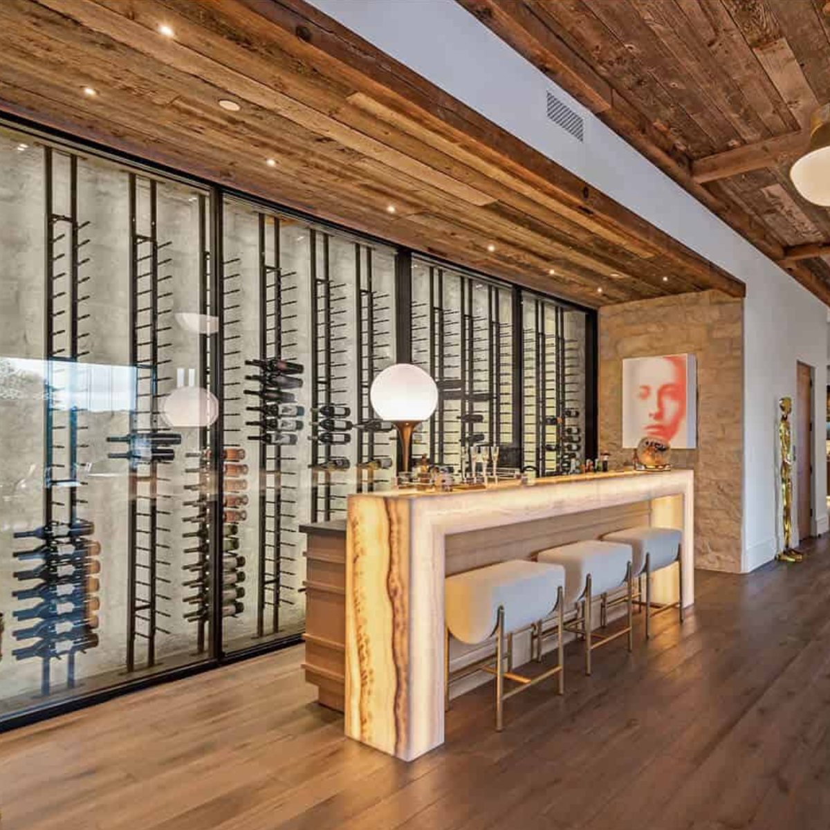 Ultra Floor-To-Ceiling Backer Channel - Luxury home bar with illuminated counter, stools, and a glass-enclosed wine wall display