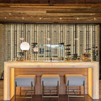Ultra Floor-to-Ceiling Mounted 1-Sided Wine Rack Display (42 Bottles) - Backlit home bar with three stools and tall vertical wine racks behind glass