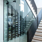 Ultra Floor-to-Ceiling Mounted 1-Sided Wine Rack Display (42 Bottles) - Glass-enclosed wine cellar built under a modern staircase with metal railings