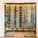 Ultra Floor-to-Ceiling Mounted 1-Sided Wine Rack Display (63 Bottles) - Glass wine cellar with stone wall and backlit racks holding bottles in a modern display