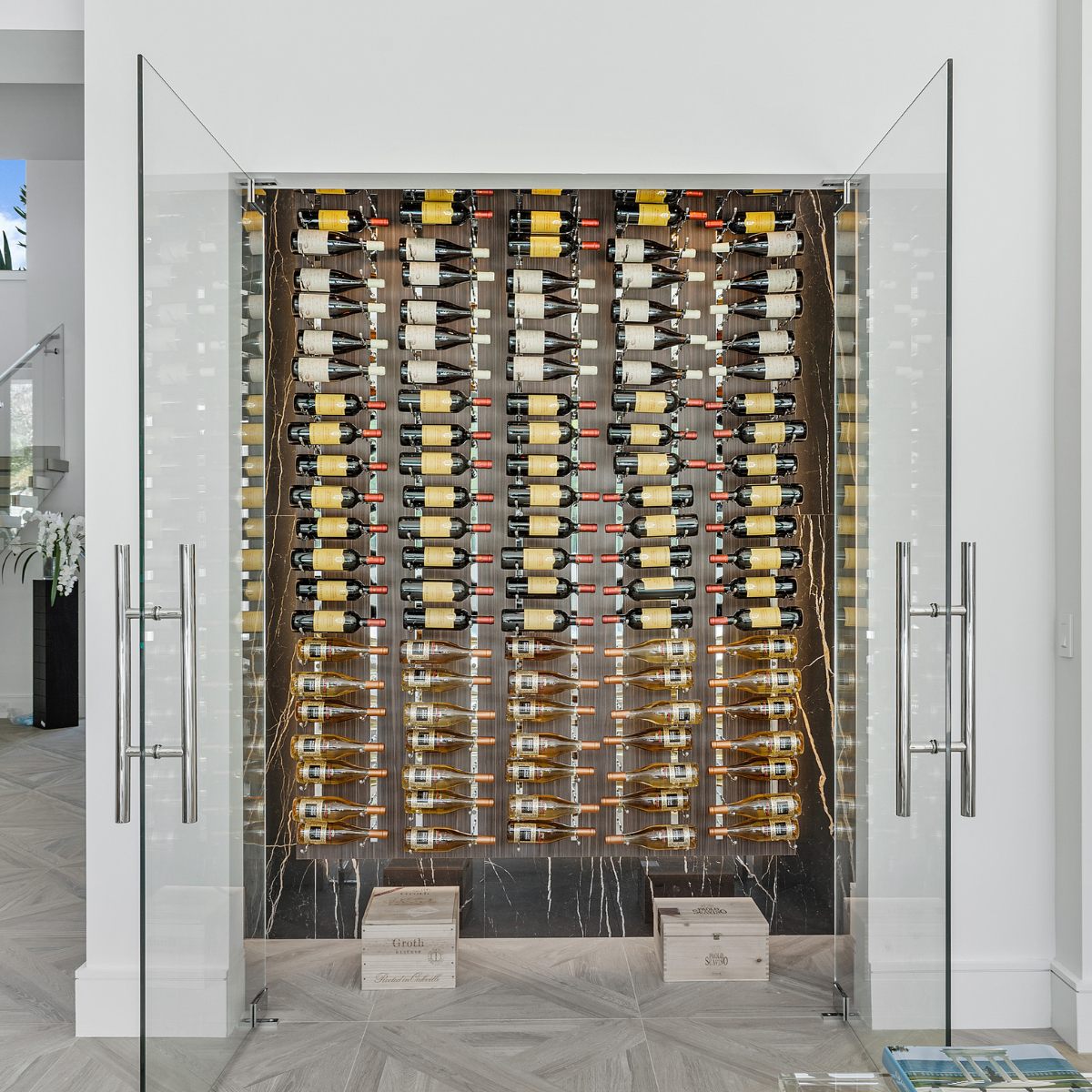 VintageView 4 inch wall mounted metal wine rack installed inside a glass enclosed wine cellar with horizontal bottle storage
