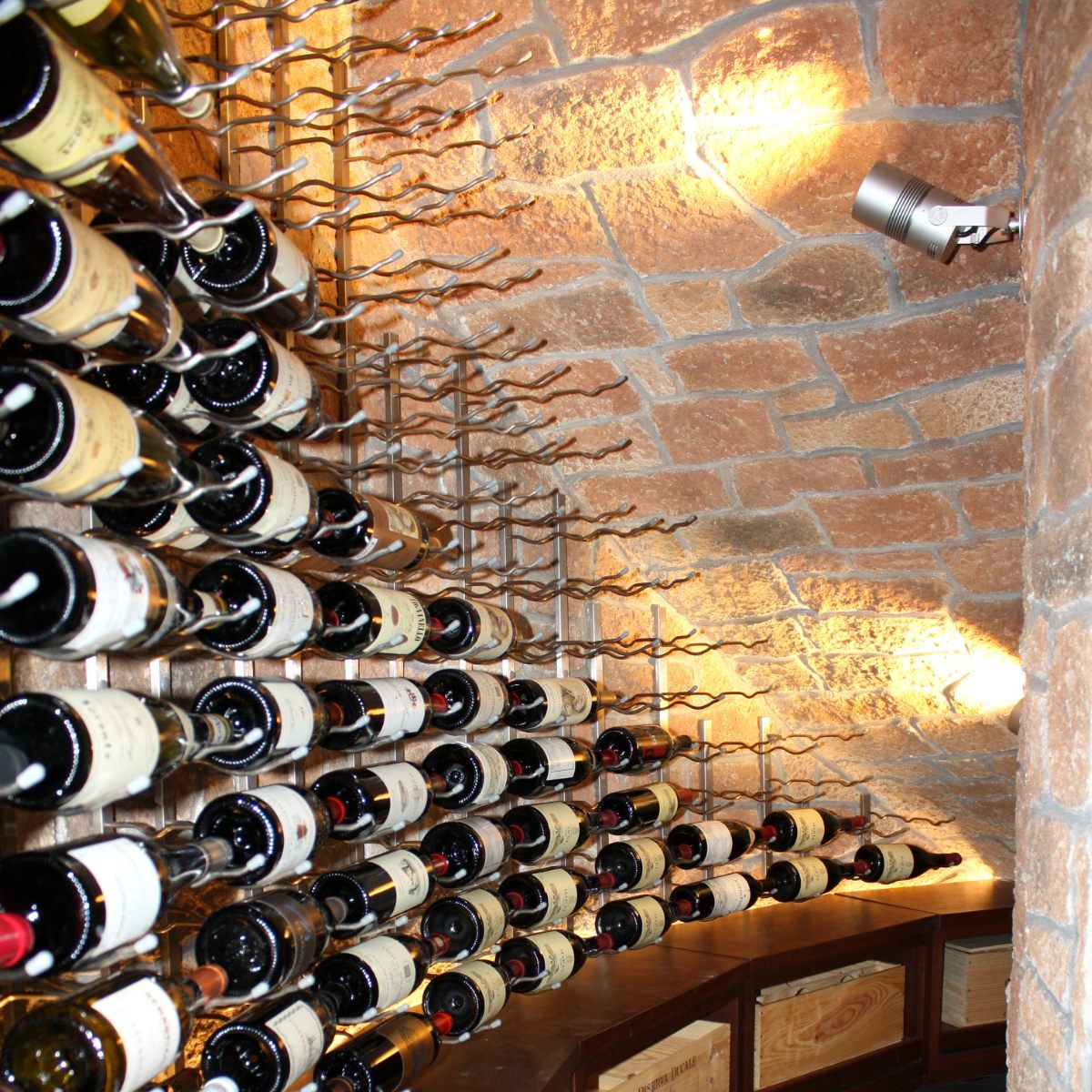 VintageView 4 inch wall mounted metal wine rack mounted on a stone wall with multi row horizontal wine bottle storage