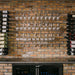 Leading wall mounted wine glass stemware rack installed on a brick wall wine bar with multiple rows of hanging glassware