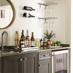 VintageView wall mounted wine glass stemware rack installed above a home bar counter with hanging wine glasses and liquor bottles